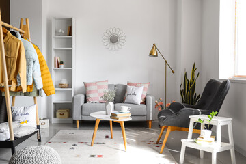 Interior of light living room with sofa and jackets