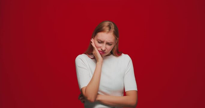 Girl suffer toothache, pain from sensitive tooth and cavities, 4k video on red background. Dental problems, caries