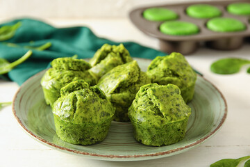 Plate with tasty spinach muffins on table, closeup