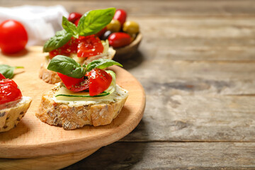 Fototapeta na wymiar Board with delicious vegetarian bruschettas on wooden background, closeup