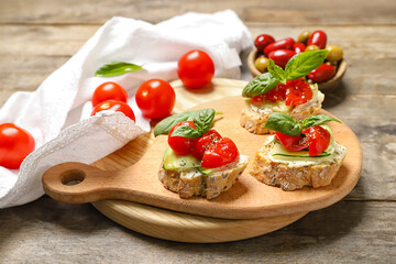 Delicious vegetarian bruschettas with vegetables in board on wooden background, closeup