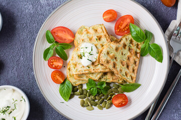 Appetizing zucchini waffles, tomatoes and pumpkin seeds on a plate on the table. Vegetable diet vegetarian food. Close-up. Top view