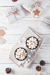 Cocoa and marshmallows in mugs and Christmas craft gifts on a white wooden table. Eco-friendly holiday. Top and vertical view