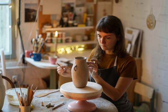 Young woman art classes student or pottery studio owner create potter vase for presentation on master class in workshop. Creative female work in artistic space relax from stress at covid-19 pandemic - Powered by Adobe