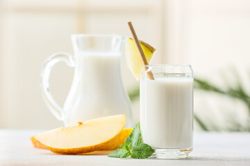 Glass and jug of tasty melon milkshake on table