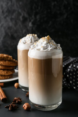 Glasses of tasty latte with nuts on black background