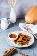 Baked pumpkin slices, honey and mint leaves on a plate on the table. Vegetarian food. Thanksgiving Day. Vertical view
