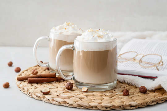Glass cups of tasty latte with nuts on white background