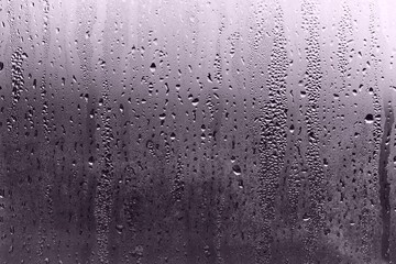 Water drops on a window in a cold, gray winter day.