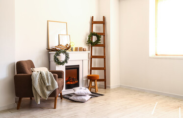 Modern fireplace and armchair in room decorated for Christmas