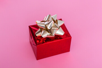 New Year Christmas composition. Red gift with a gold bow on a pink background. Top View Copy Space