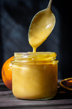 vista frontal de una cuchara saliendo de un tarro de cristal con crema de naranja