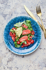 Tasty salad with salmon and vegetables on color background
