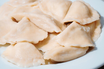 Fototapeta na wymiar Serving of traditional Polish pierogy dish on a white plate. Dumplings filled with meat, cheese and mushrooms. Popular Eastern European food