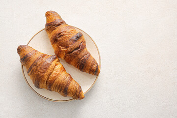 Plate with tasty homemade croissants on light background