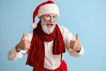 Fototapeta na wymiar Happy Santa Claus showing thumb-up on color background