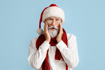 Fototapeta na wymiar Portrait of surprised Santa Claus on color background