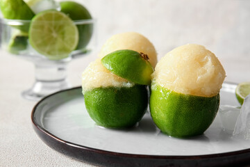 Plate with tasty ice creams in lime peels on light background