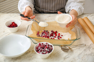 Woman preparing tasty sugared cranberry in kitchen