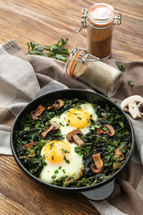 Frying pan with tasty Shakshouka on wooden background