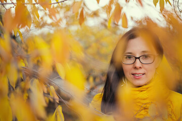 beautiful woman in a yellow jacket and scarf on an autumn forest background