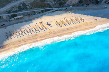 Top view aerial drone photo of Myrtos beach with beautiful turquoise water, sea waves and straw...