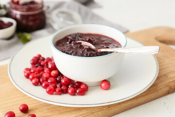 Bowl with tasty lingonberry jam and fresh berries on white background