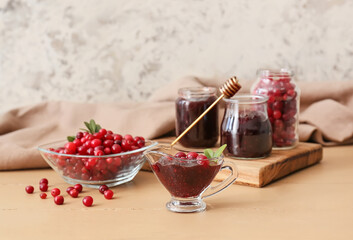 Gravy boat with tasty lingonberry jam and fresh berries on table