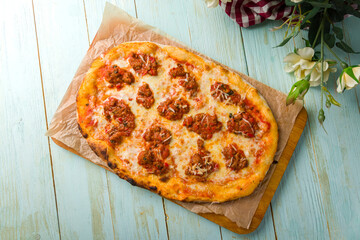 Roman pizza with meat bolognese on Roman dough, pinsa isolated on mint wooden table top view