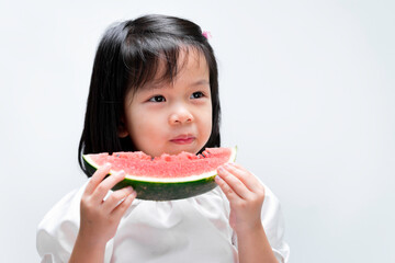 Portrait of beautiful black haired little girl eating red watermelon healthy fruit snack. Adorable Asian child holding vegetable food. On isolated white background.