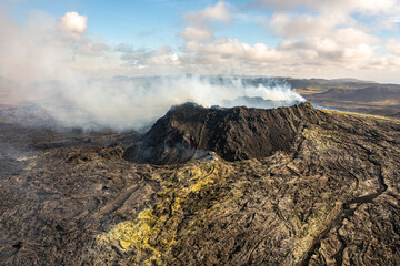 Aerial drone view of Fagradsfjall volcano in Iceland. Smoke is spewing out of volcano, black lava landscape.