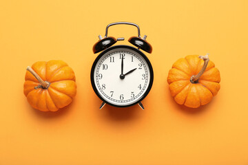 Alarm clock and pumpkins on color background. Harvest time