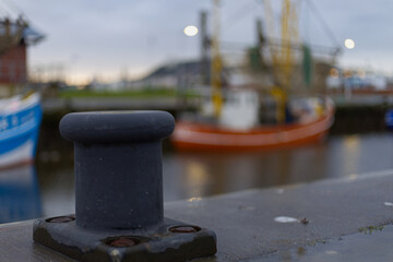 close up of a bollard in front of a fish trawler in a port