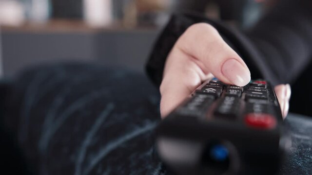 cinematic woman with manicure switches channels, watch tv at home, close-up