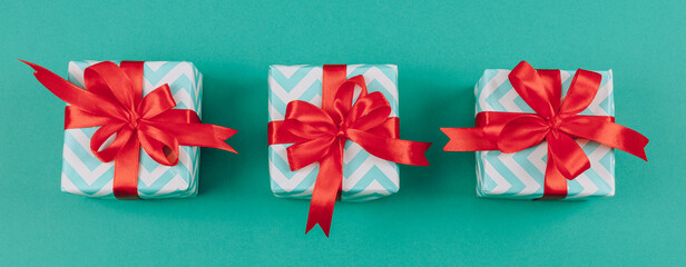 Three small striped gift boxes with bow ribbons lie in the middle on a green background.