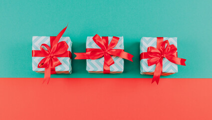 Three small striped gift boxes with bow ribbons lie in the middle against a green and red background.