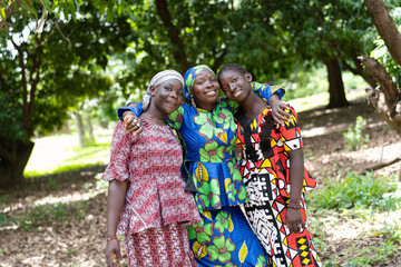 Three proud African women standing in the green showing off their new colourful dresses