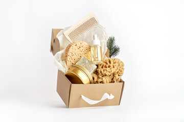 Natural sea sponges, soup, cosmetic bottle with oil or serum in craft box on white. Creative...