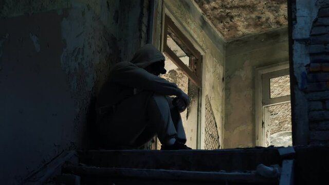 The guy is crying. Lonely person in an abandoned house in sadness or depression. The man has problems. Upset person, social problems