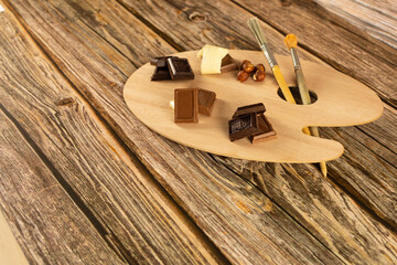 Assorted chocolates are set on an artistic palette against a warm wooden background.