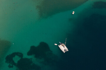 Aerial shot of moored catamaran on turquoise sea on a reef in Greece