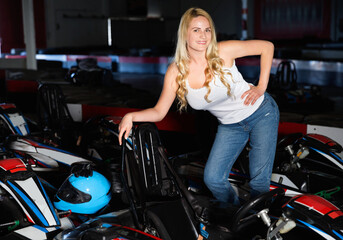 Sexy cheerful positive smiling woman standing near sport cars for karting in sport club