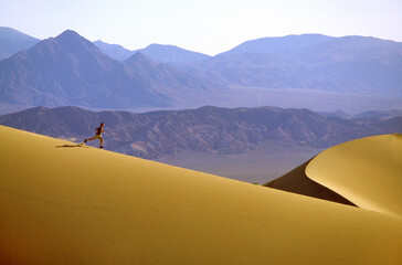 Bucky Brownell running dunes at Stovepipe Wells w/ Funeral Mts in background  at Death Valley National Park, CA / USA