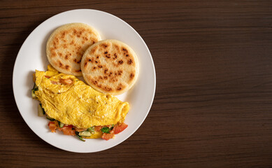 Venezulan food with arepas and omelette on a wooden background