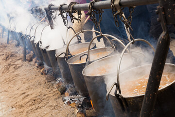 Preparation of food in medieval style in open-fire boilers during city holiday outdoors