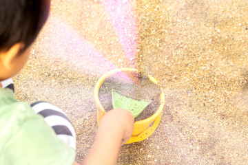 砂遊びに夢中の男の子　緑のスコップと黄緑色のバケツで砂遊び