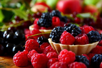Summer berries dessert still-life. Mix ripe fresh berries bramble, blackberry, raspberries in basket, cherries close up on blurred background of bird cherry and apple. Selective focus on first basket