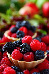 Summer berries dessert still-life. Mix ripe fresh berries bramble, blackberry, raspberries in basket, cherries close up on blurred background of apple. Selective focus, vertical frame