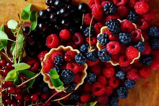 Summer berries dessert still-life. Mix ripe fresh berries bramble, blackberry, raspberries in basket and bird cherry on wooden table. Top view