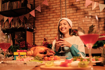 Young caucasian woman happiness smile at a diner with special foods such as roasted turkey and wine in Christmas celebration party in dining room decorated for cheerful festival and happy new year.